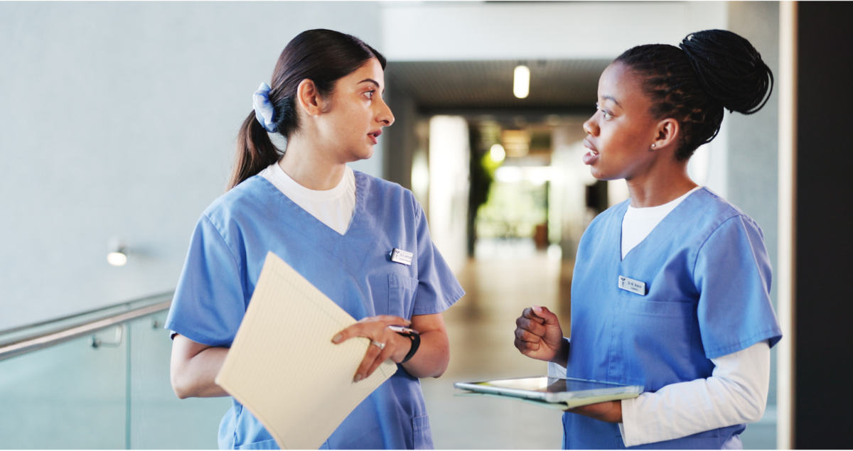 Two clinicians speaking in clinic hallway.