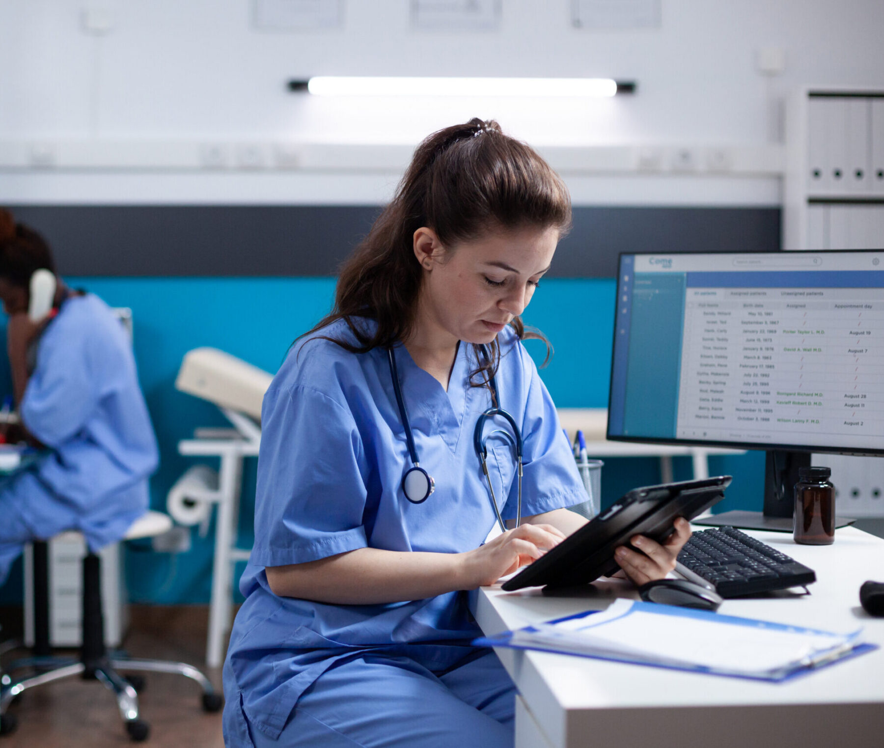 Nurse reviewing a tablet in a clinic.