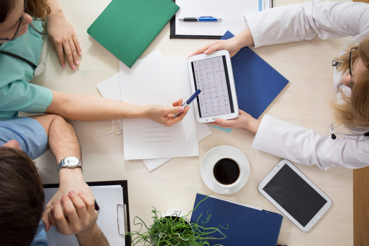 Aerial view of three clinicians reviewing ECG results.